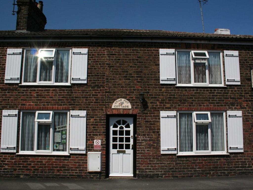 a brick building with white windows and a door at Crab pot cottage in Flamborough