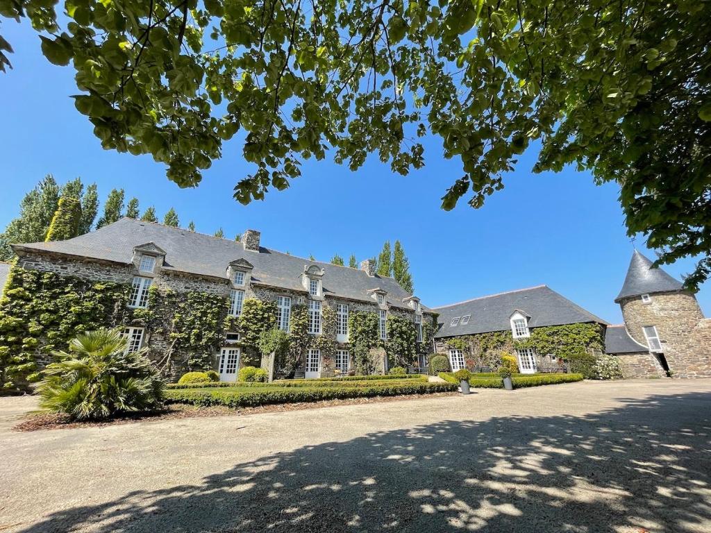 una gran casa de ladrillo con un árbol delante en Manoir de la Bégaudière, en Mont-Dol