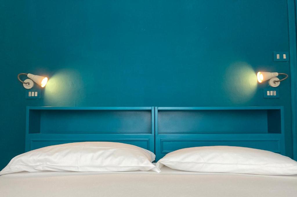 una camera blu con un letto con due cuscini bianchi di Hotel Nizza Creative Hotel a Rimini