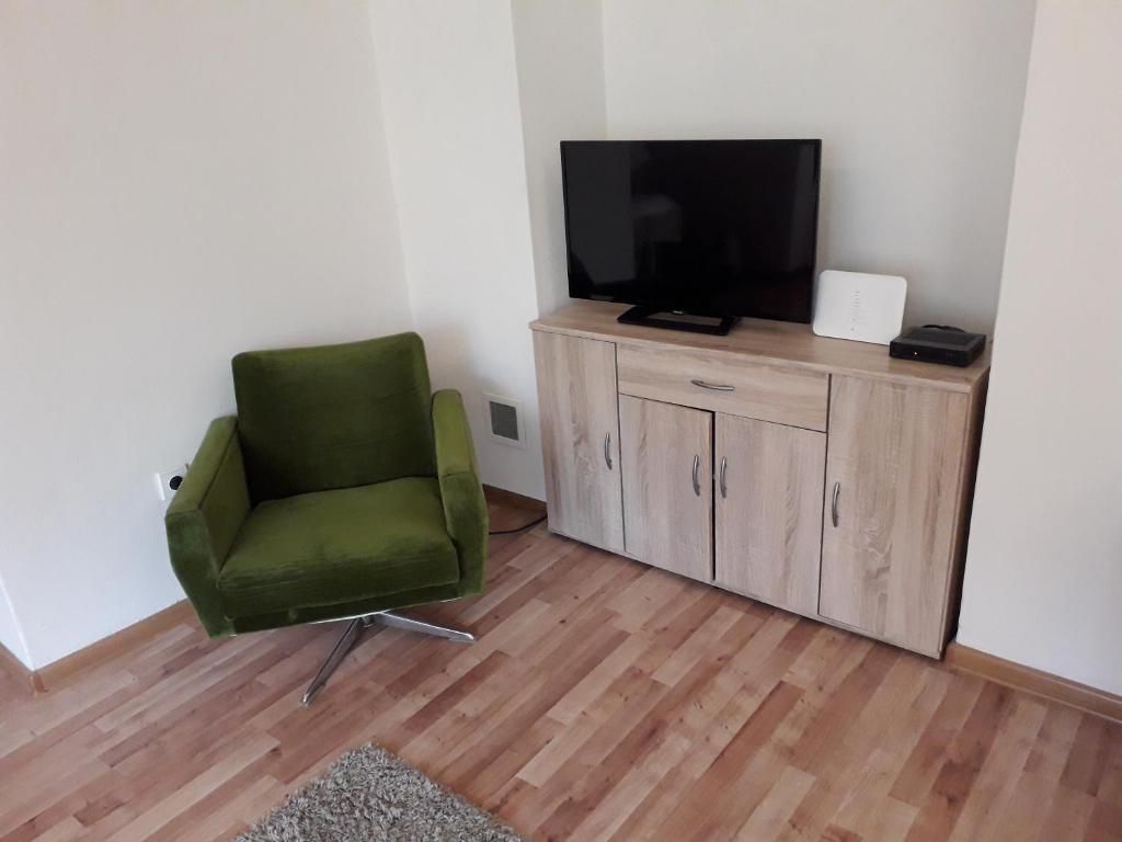une chaise verte assise dans une pièce avec une télévision dans l'établissement Kapitula centrum, à Banská Bystrica