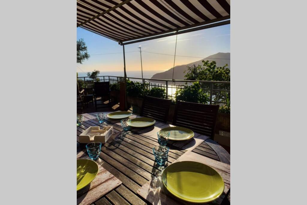 un tavolo con piastre verdi su una terrazza con vista di Cherry’s house sea view citra 010037-LT-0449 a Moneglia