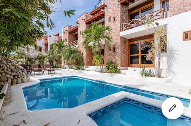 a swimming pool in front of a house at HOTEL VILLAS XAIBA in Puerto Escondido