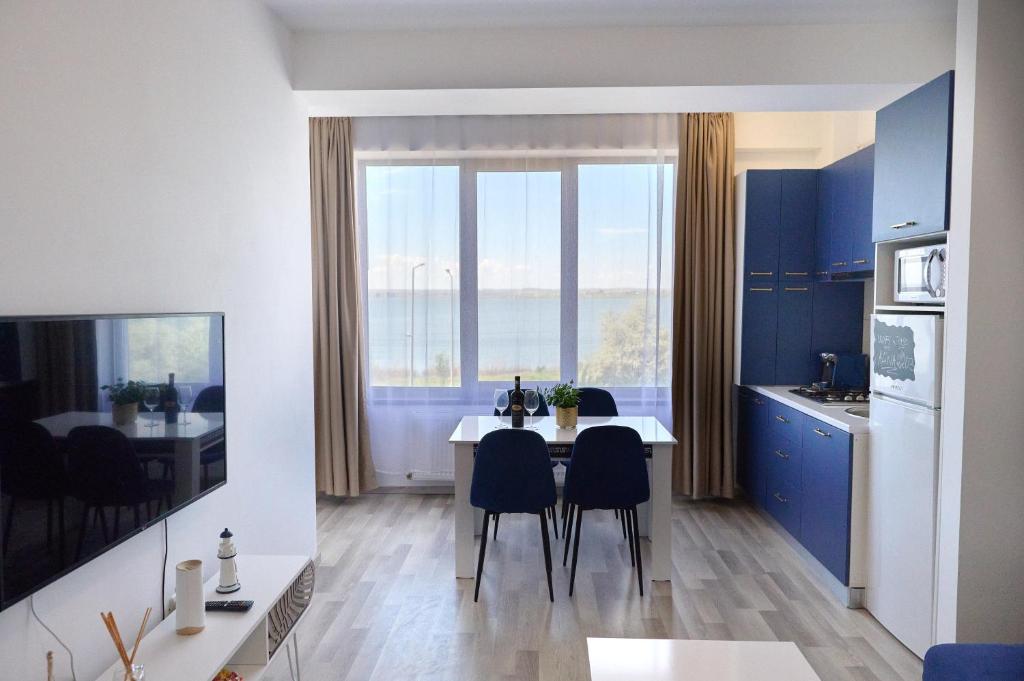 a kitchen with a table and chairs and a large window at Alina Lake View Apartment in Mamaia