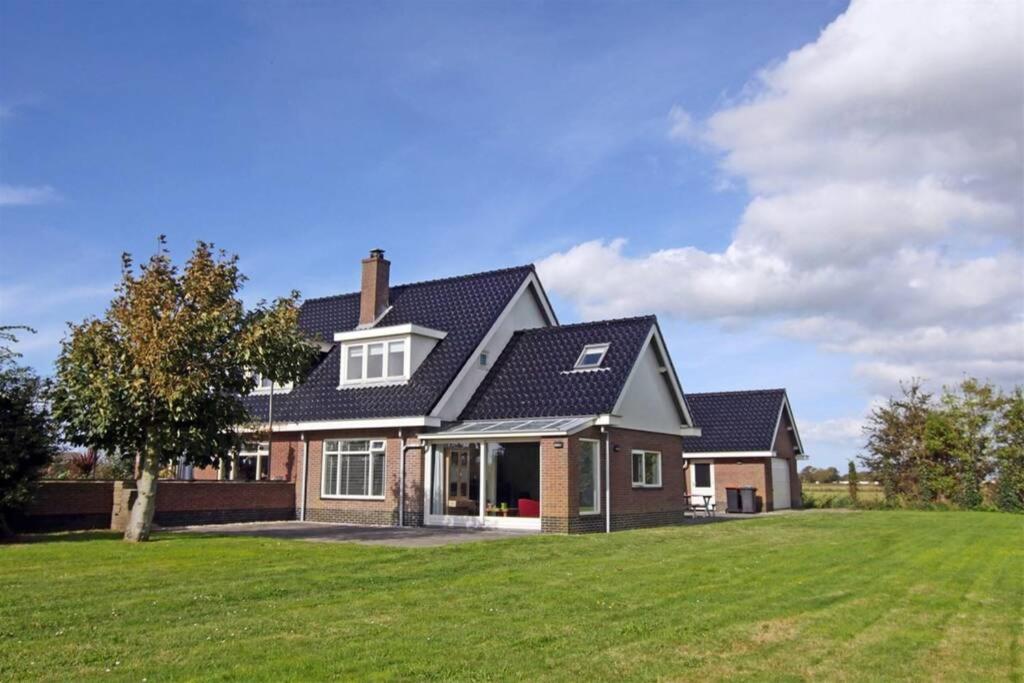 a house with a green lawn in front of it at Familiehuis Dacha op de Slufterweg in De Cocksdorp
