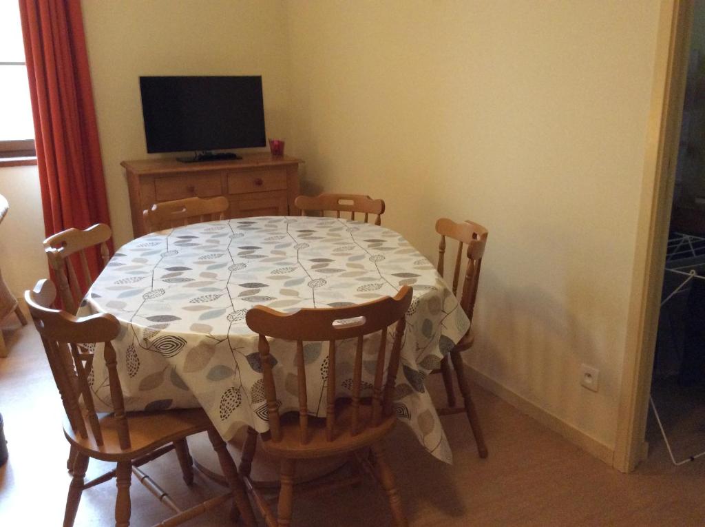 a dining room table and chairs with a table and a television at Résidence Grand Hôtel in Aulus-les-Bains