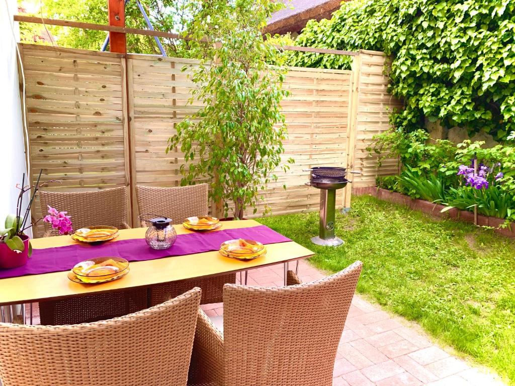 a table and chairs in a backyard with a fence at Balaton Apartman in Balatonföldvár