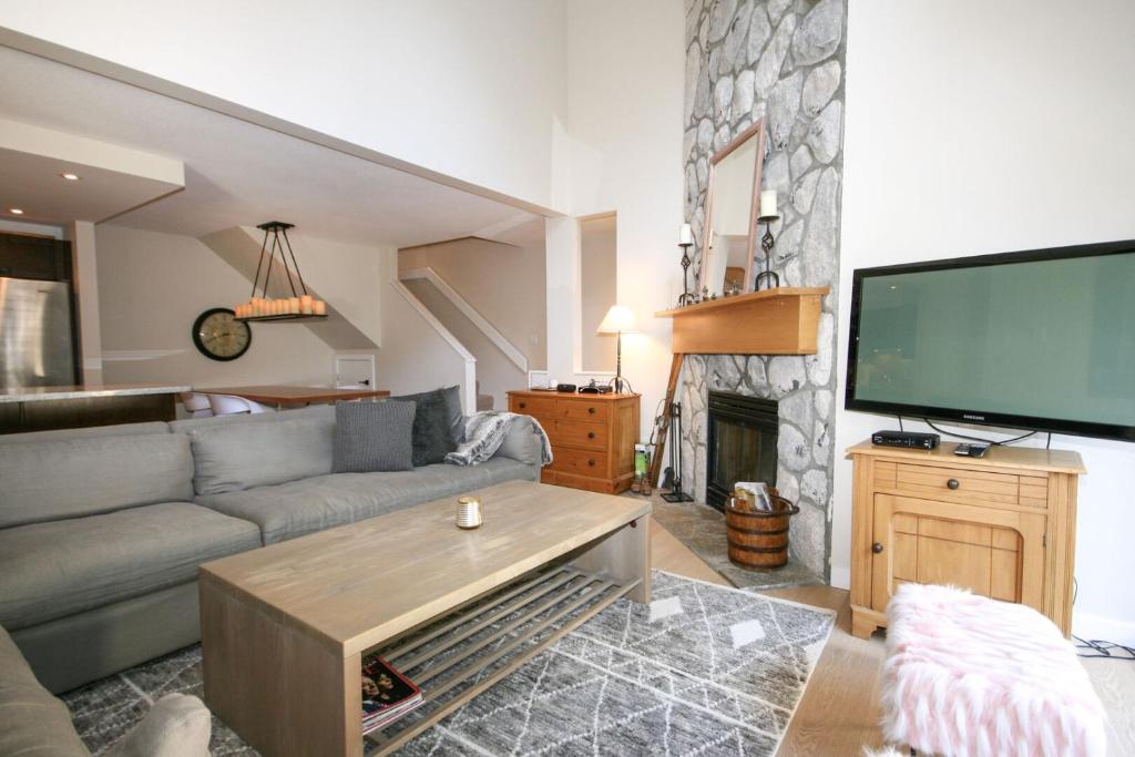 ein Wohnzimmer mit einem Sofa und einem großen TV in der Unterkunft Modern Home with Forest Views by Harmony Whistler in Whistler