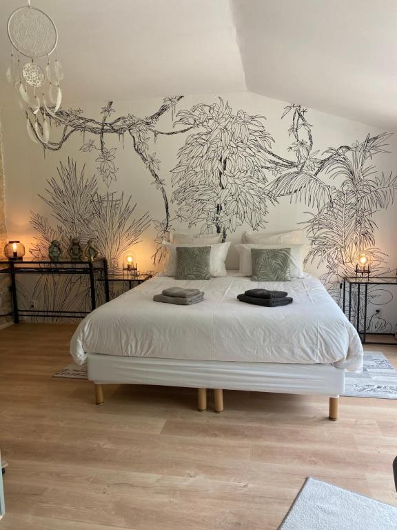 a bedroom with a white bed with a mural on the wall at La Chaumeauniere in Aigrefeuille-dʼAunis