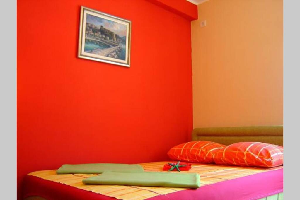 a bedroom with an orange wall and a bed at Apartman Budva Ivana in Budva