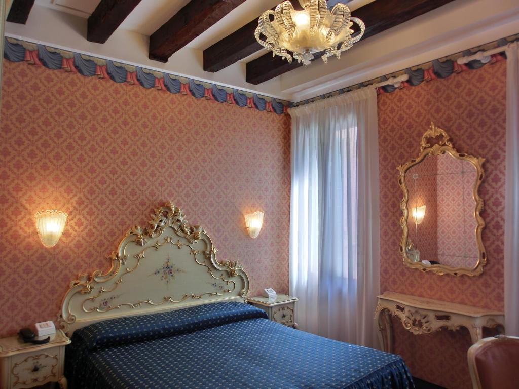 a bedroom with a blue bed and a chandelier at Hotel Diana in Venice