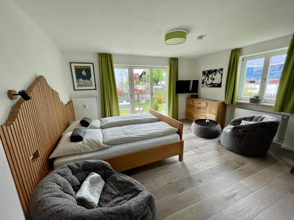 a bedroom with a bed and two chairs and a television at BÄRENALP Ferienwohnen in Garmisch-Partenkirchen