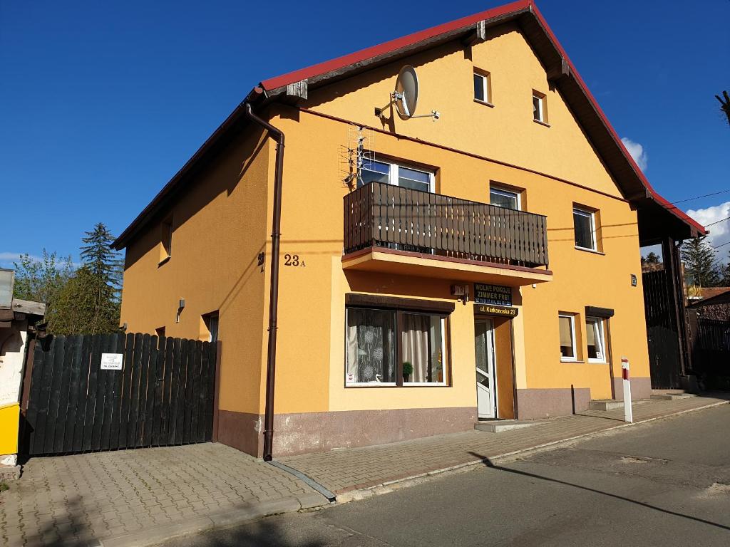 a yellow building with a balcony on a street at Pokoje Karkonosze in Przesieka