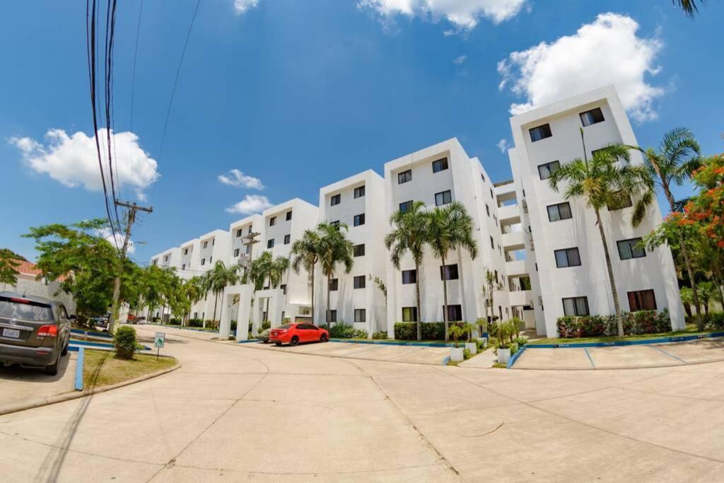 um grande edifício de apartamentos branco com estacionamento em Departamento Planta Baja con parqueo en Condominio em Santa Cruz de la Sierra