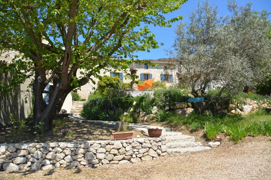 a garden with a stone wall and a tree at Mas Renard in Beauvoisin