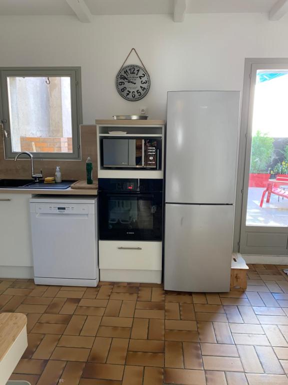 a kitchen with a white refrigerator and a microwave at Appartement la corde a linge Gruissan village avec terrasses in Gruissan