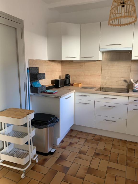 a kitchen with white cabinets and a wooden floor at Appartement la corde a linge Gruissan village avec terrasses in Gruissan