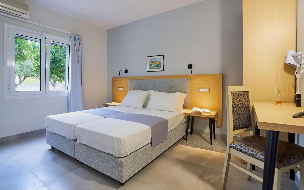 een slaapkamer met een groot bed en een bureau bij Sergiani Garden Hotel Apartments in Stalida