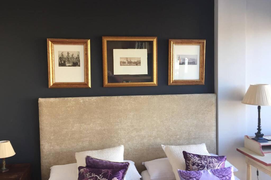 - une chambre avec 3 photos encadrées au-dessus d'un lit et des oreillers violets dans l'établissement IMAGEN SUITE, à Séville