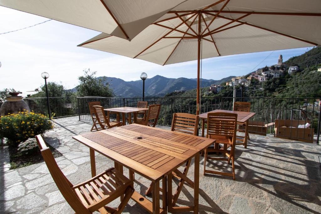 un patio con mesas, sillas y una sombrilla en Agriturismo Eos, en Levanto