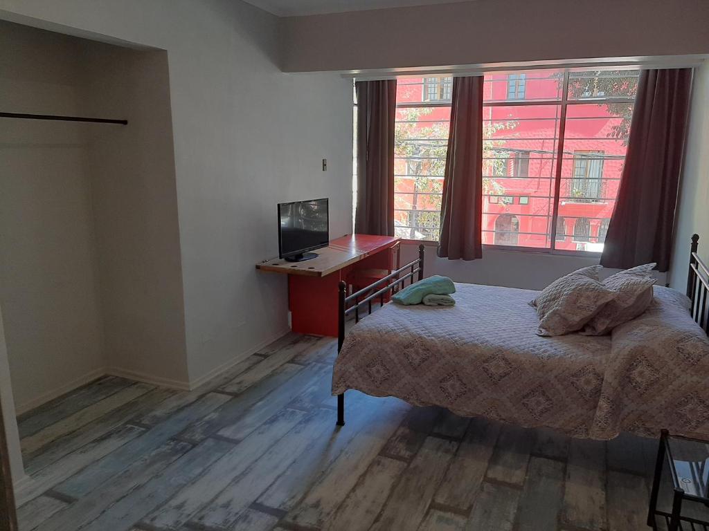 a bedroom with a bed and a desk and a television at Aji Hostel in Santiago