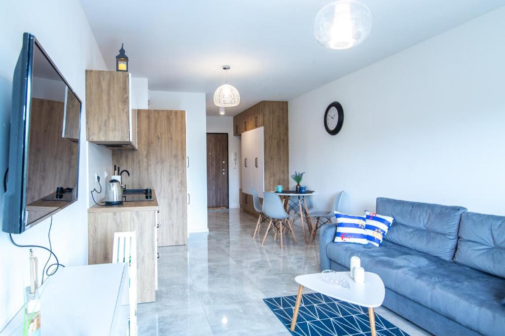a living room with a blue couch and a kitchen at Apartament Blue Na Wydmach in Międzywodzie