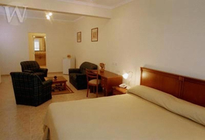 1 dormitorio con 1 cama y sala de estar con sillas en Wilson Hotel en Salta