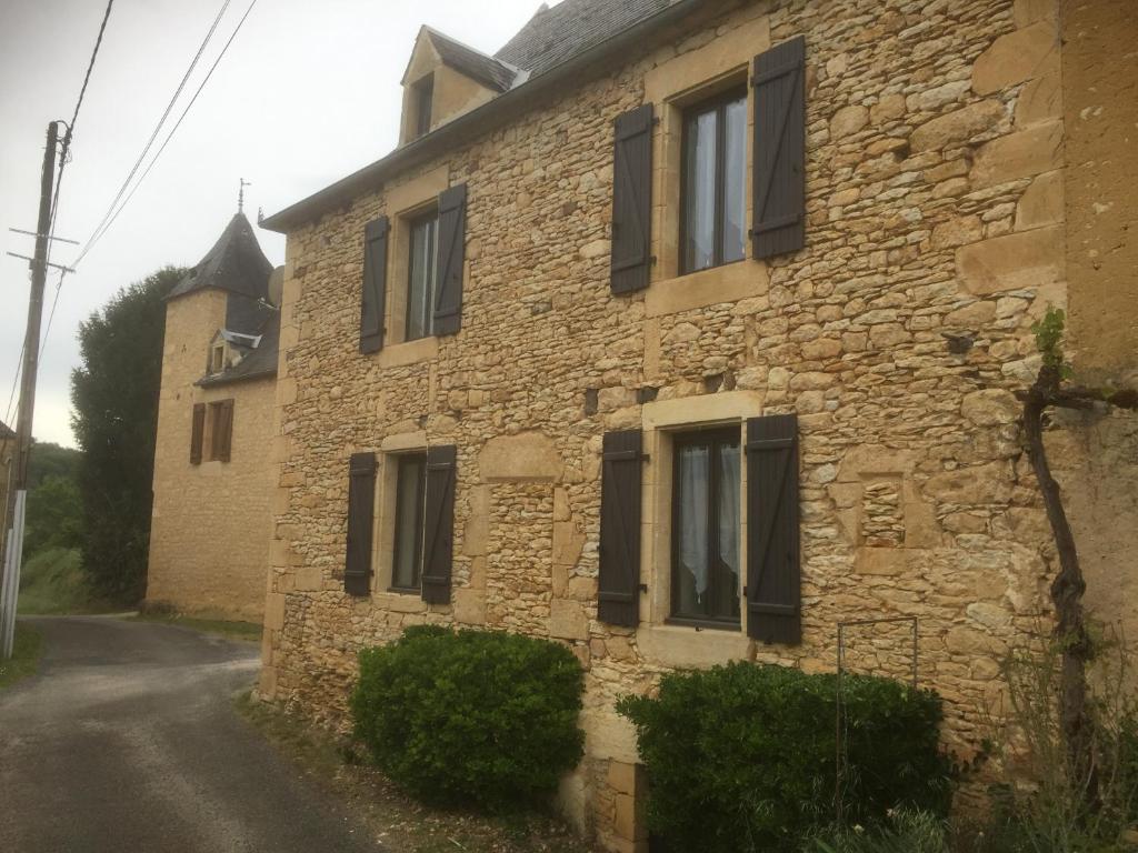une vieille maison en pierre avec des volets noirs dans une rue dans l'établissement Maison 5 pièces dans hameau pittoresque très calme, à Payrac