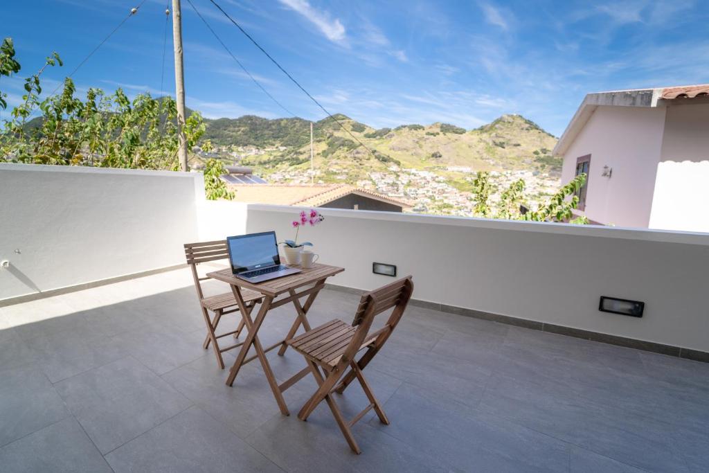 a table and chairs on a balcony with a laptop at Fernandes House in Machico