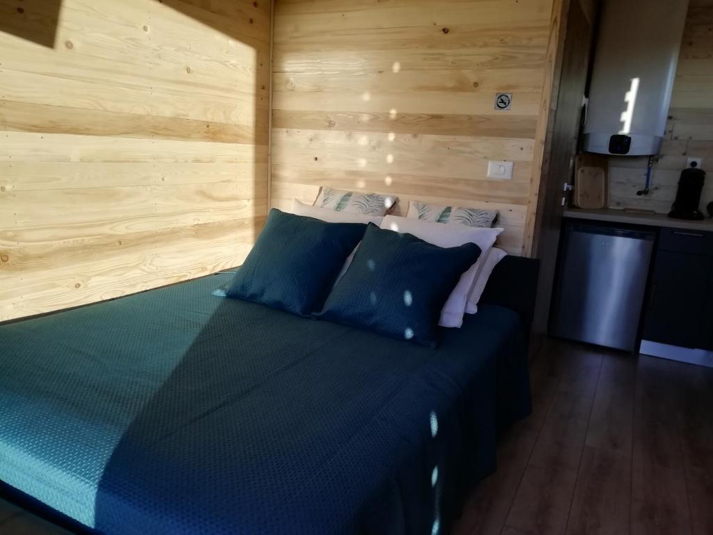 a bed in a room with a wooden wall at Lodge avec vue panoramique in Saint-Sorlin