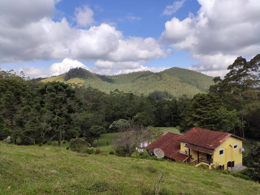 a house in a field with mountains in the background at Sitio na Serra da Mantiqueira Águas do Canjarana in São Francisco Xavier