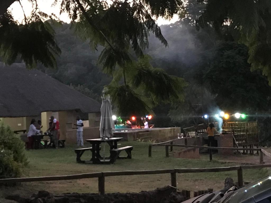 una mesa con una sombrilla en un campo por la noche en Siyaya’s Guest Palace, en Jozini