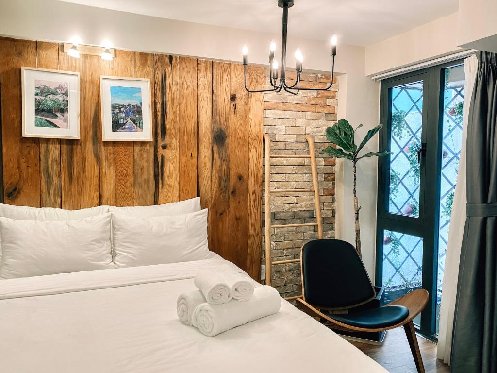Un dormitorio con una cama blanca y una silla negra. en Petite Dalat - Boutique Hotel, en Da Lat