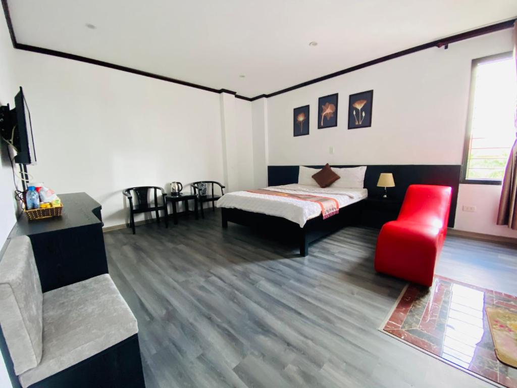 Khách sạn Hoàng Gia في Thái Bình: غرفة نوم بسرير وكرسي احمر