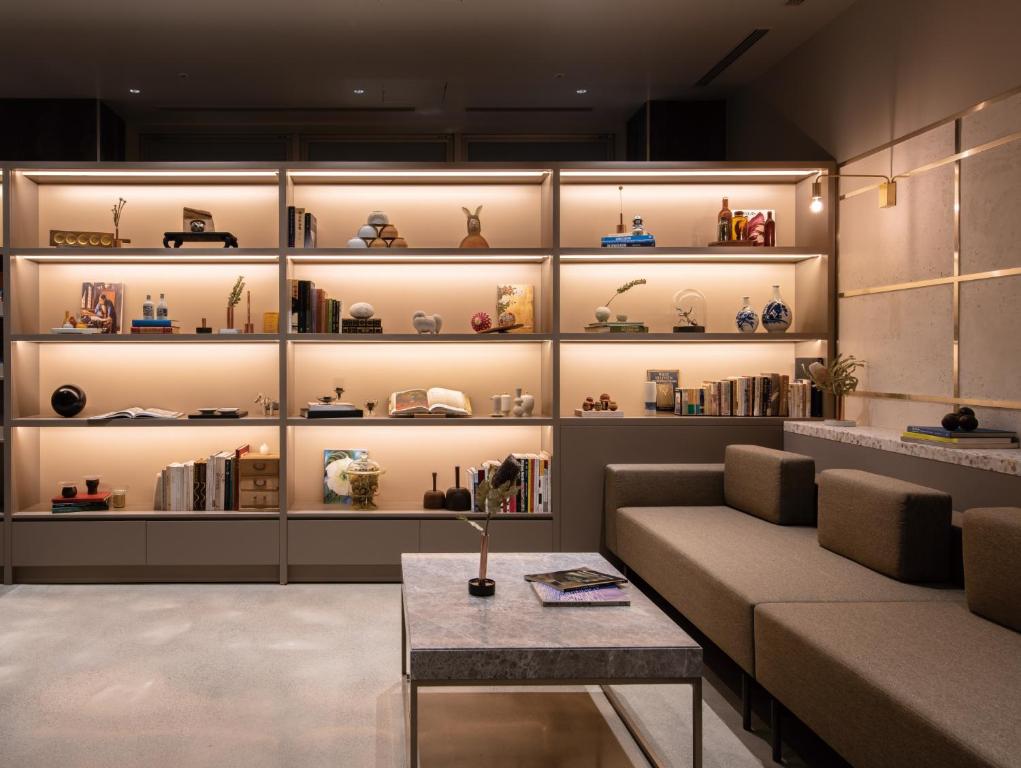 a living room with a couch and shelves of vases at HOTEL TORIFITO KANAZAWA in Kanazawa