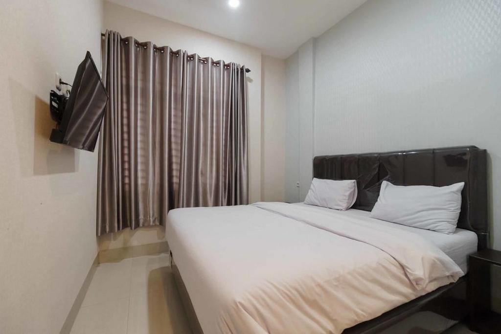 - une chambre avec un grand lit blanc et une fenêtre dans l'établissement Seindo Hotel Mitra RedDoorz, à Sunggal
