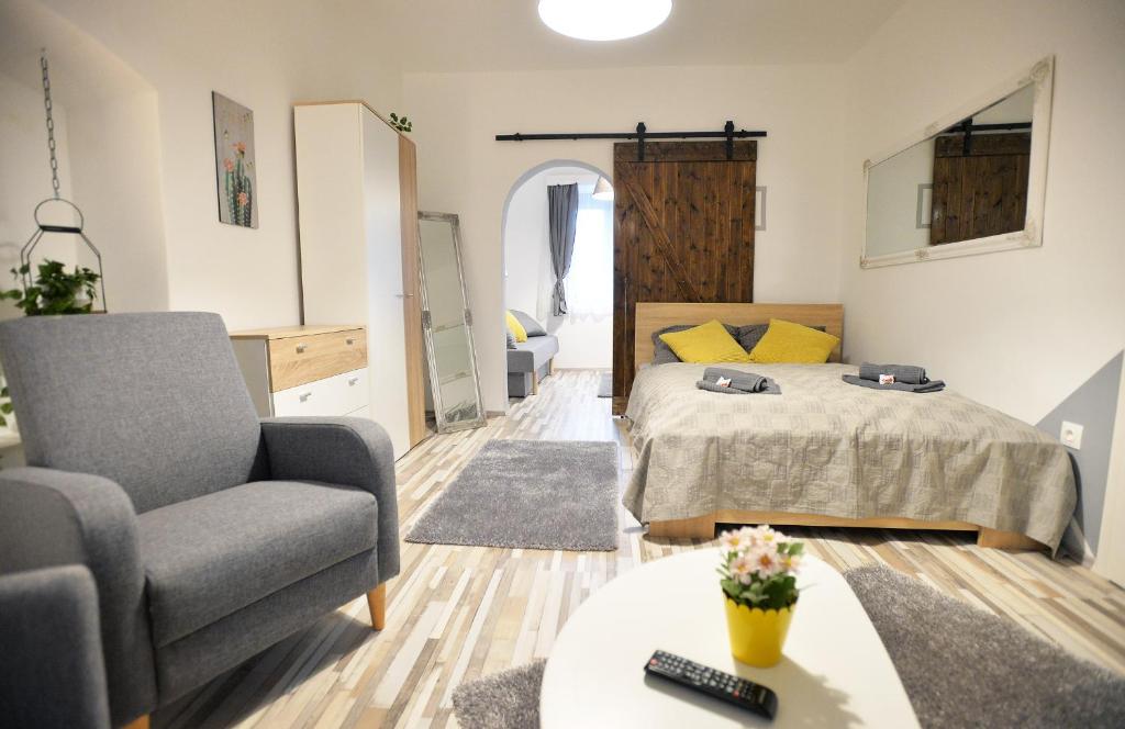 een woonkamer met een bed, een stoel en een tafel bij Castle Garden Apartman in Eger