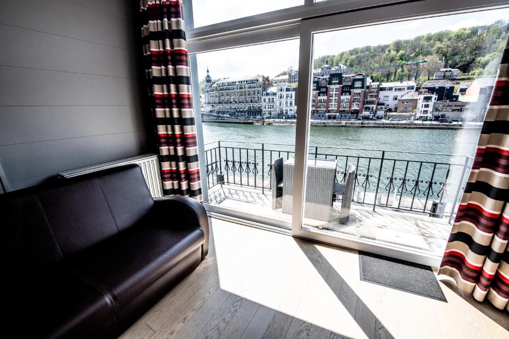 a room with a couch and a window with a view of the water at L'Inattendu "sur la croisette" Dinant centre in Dinant