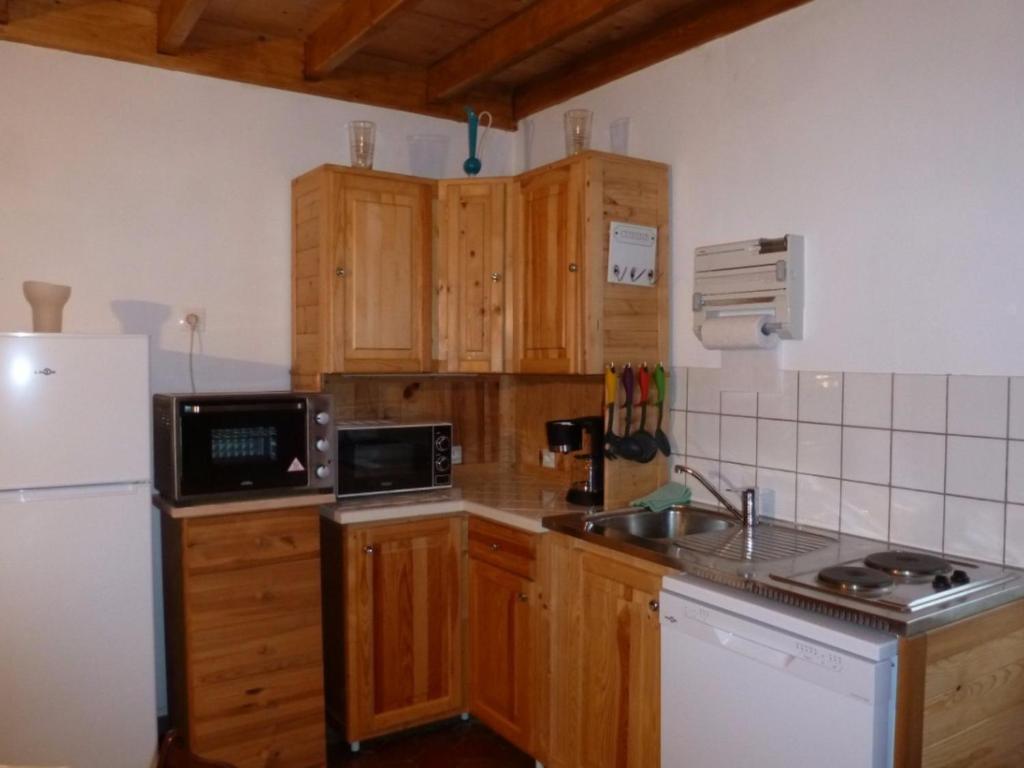 a kitchen with wooden cabinets and a white refrigerator at Gîte Fiefs, 2 pièces, 2 personnes - FR-1-376-1 in Fiefs