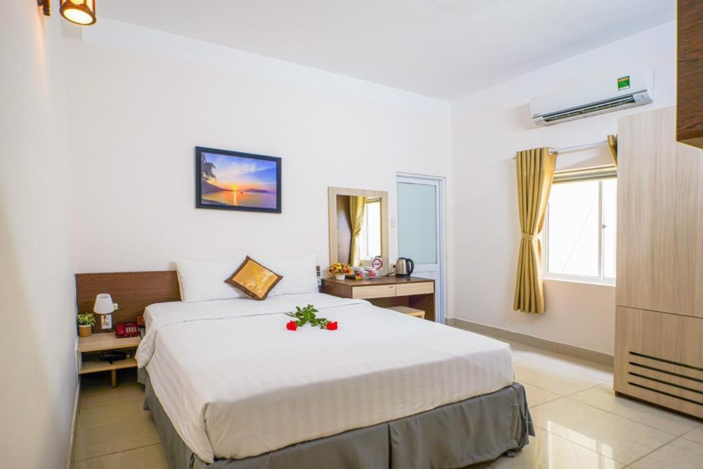 巴地市Ruby Hotel Côn Đảo的卧室里有一张白色的大床，床上摆着鲜花