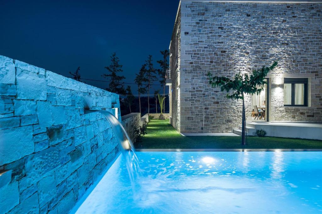 a swimming pool in front of a brick building at night at Villa Eleana in Pitsidia