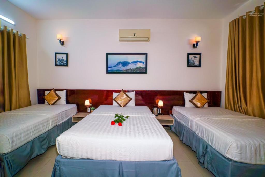 巴地市Ruby Hotel Côn Đảo的配有两张带鲜花的桌子的床的酒店客房