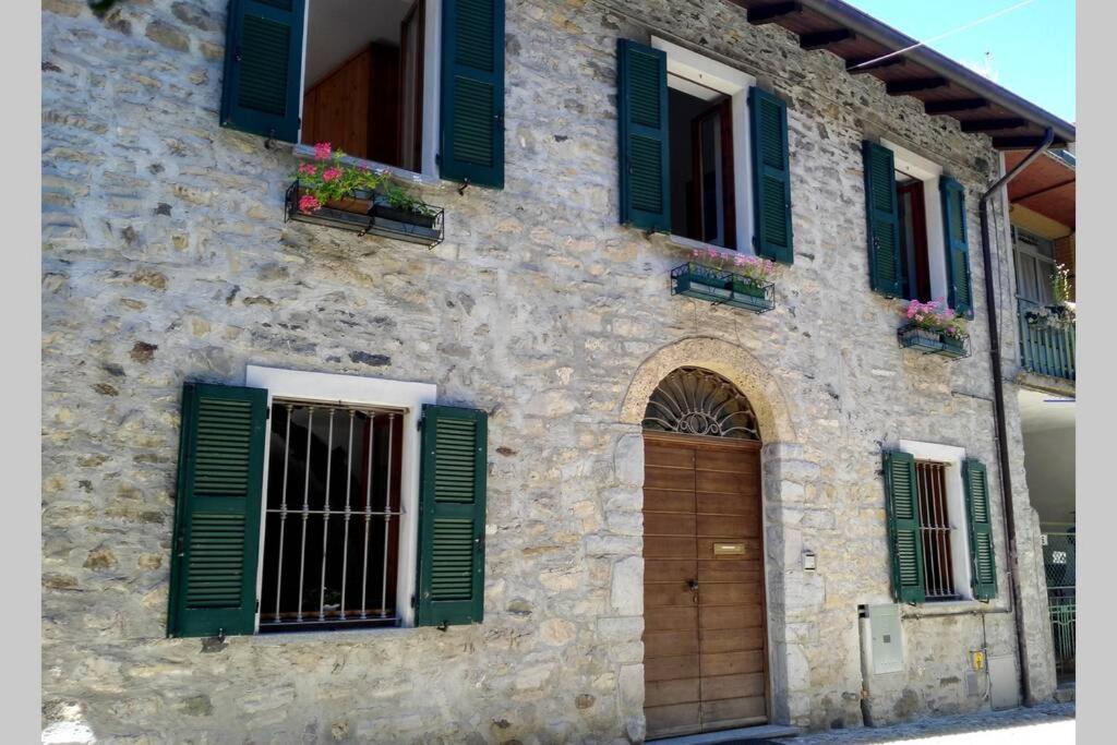 a stone building with green shutters and a door at Casa Almut & More - Lake Como Center - Varenna in Perledo