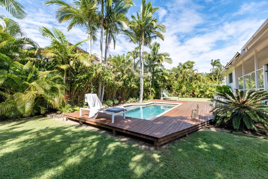 een achtertuin met een houten terras en een zwembad bij Pura Vida in Noosa Heads