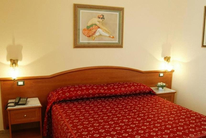 um quarto com uma cama vermelha e uma fotografia na parede em Hermitage Capua Hotel em Capua
