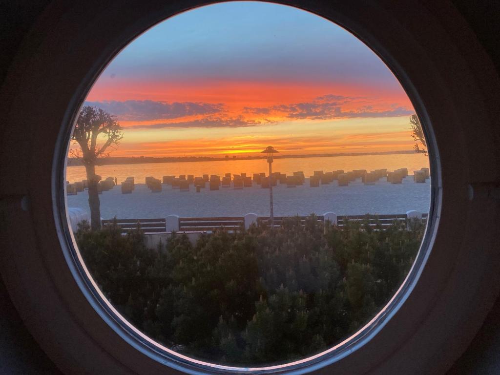 une fenêtre ronde avec vue sur le coucher du soleil dans l'établissement Windjammer Eagle, à Laboe