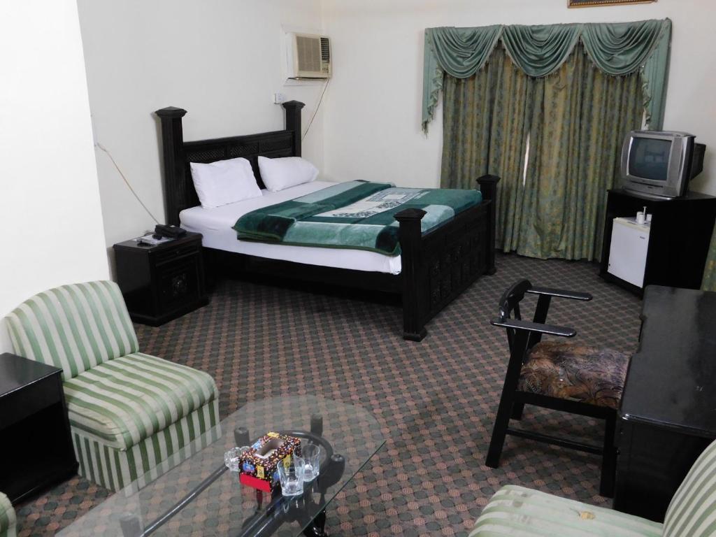 a bedroom with a bed and a chair and a tv at The City Lodge in Islamabad