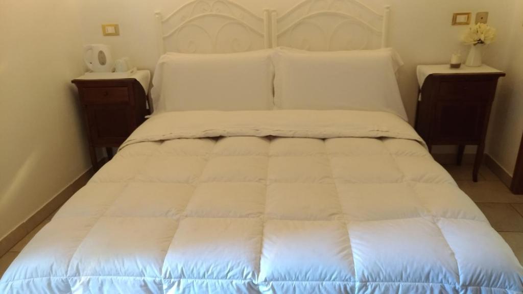 a large white bed in a room with two tables at B&B DIMORA PALMIERI in Monopoli