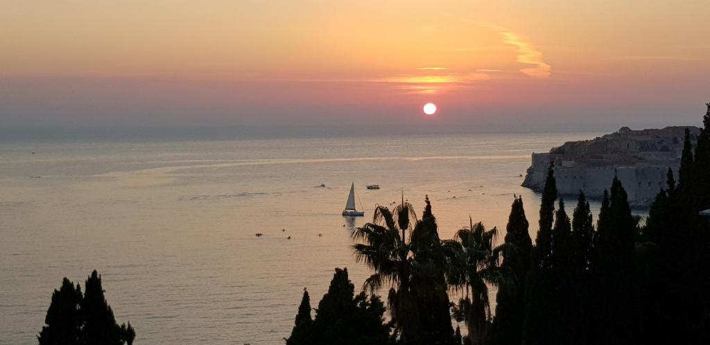 una puesta de sol sobre el océano con un velero en el agua en Apartments Sv.Jakov, en Dubrovnik