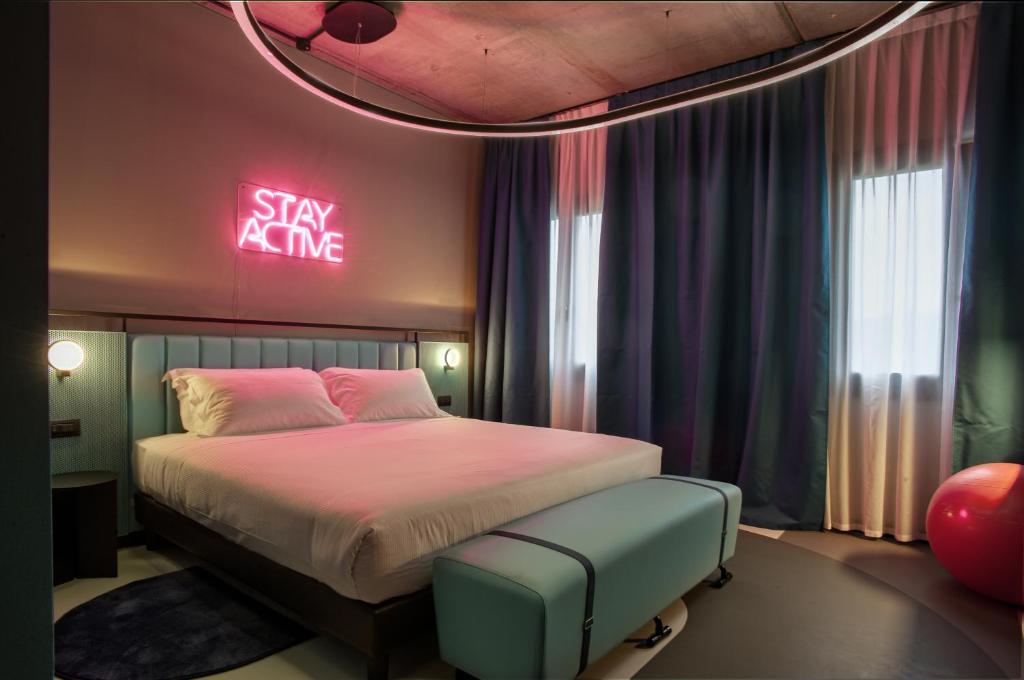 BrunelloにあるStay Hotelのベッドルーム1室(ベッド1台、ネオンサイン付)