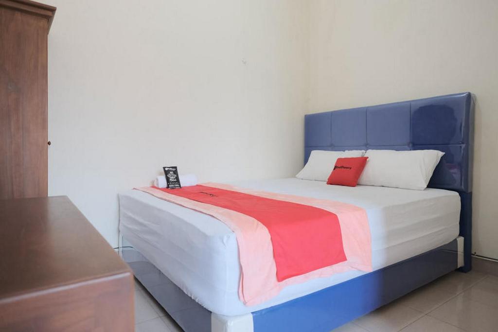 a bed with a blue and red blanket on it at RedDoorz Syariah near Gatot Subroto Lampung 4 in Lampung